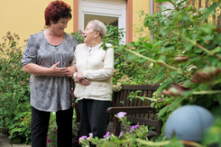 Bewohnerin mit Pflegefachkraft im Garten